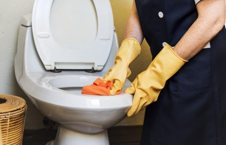 Nettoyage et entretien hygiénique d'un WC avec gants de protection et chiffon.