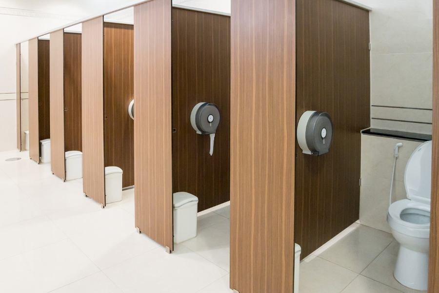 Alignement de cabines de toilettes publiques modernes avec distributeurs de papier et douchettes.