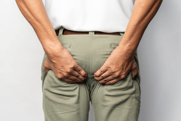 Homme se grattant les fesses à travers son pantalon beige