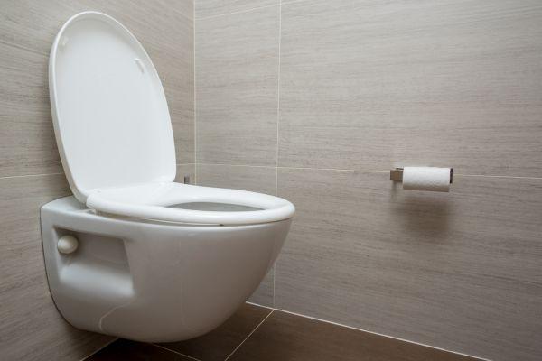 Vue d'un WC suspendu blanc avec abattant ouvert dans une salle de bain moderne.
